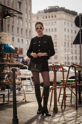 a lady in a black tweed jacket and a pair of black shorts